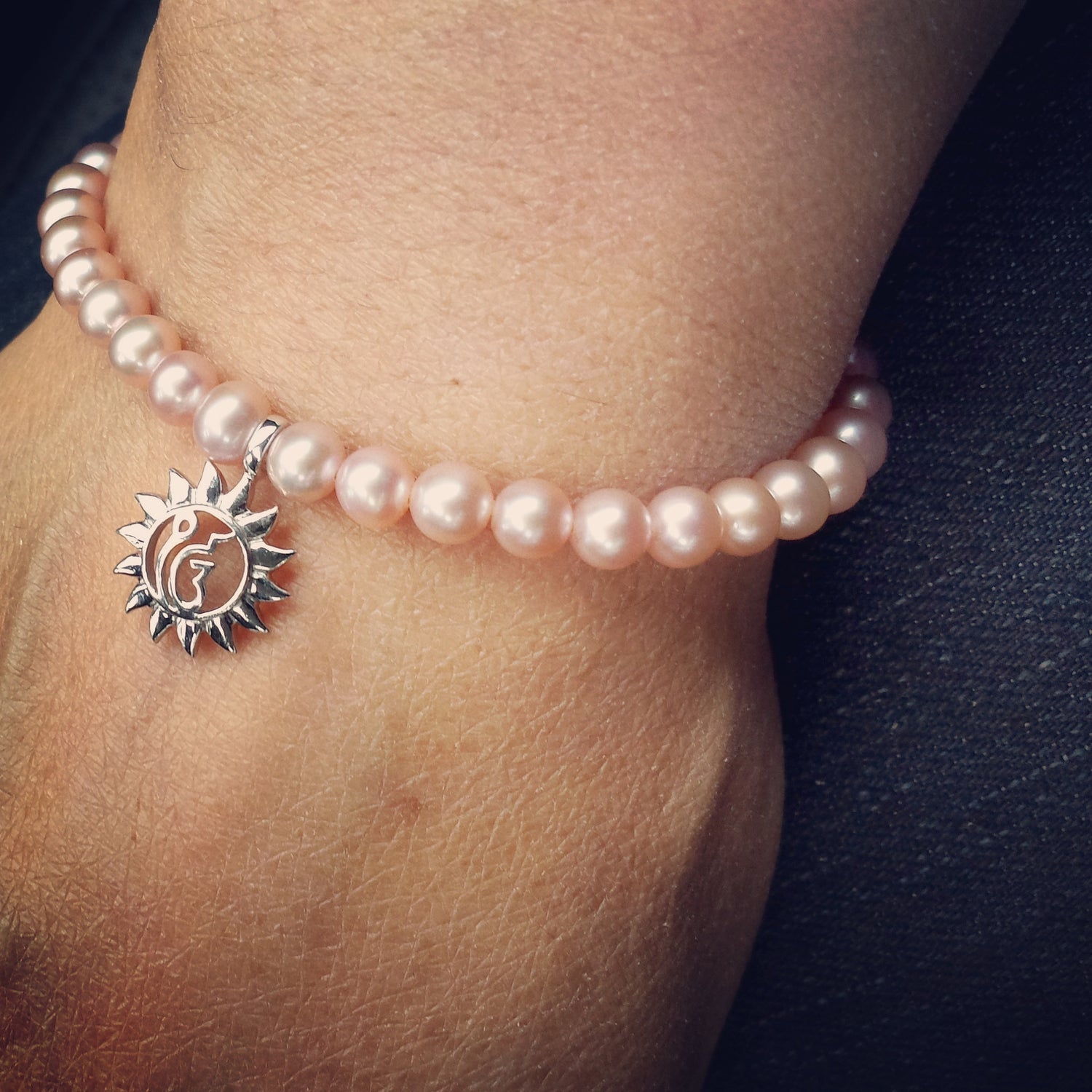 Finest quality string of baby pink cultured freshwater pearls with a 13mm sterling silver charm featuring the ik Oankar symbol meaning one divine creator for moments of self reflection and  connection .